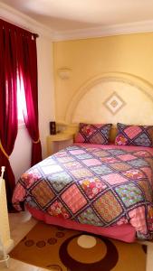 a bedroom with a bed with a colorful quilt at Chez Eric in Akhfennirr