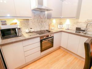 a kitchen with white cabinets and a microwave at The River Appartment in Todmorden