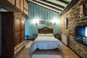 1 dormitorio con cama y pared de piedra en POSADA RURAL SIERRA de IBIO, en Villanueva de la Peña