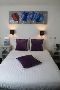 a bedroom with a large white bed with purple pillows at De Doelen in Leiden