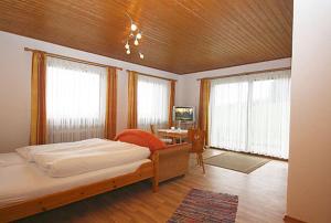 Schlafzimmer mit einem Bett, einem Tisch und Fenstern in der Unterkunft Gästehaus Annemarie in Rimsting