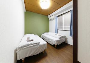 twee bedden in een kleine kamer met een raam bij Osaka - Hotel / Vacation STAY 23784 in Osaka
