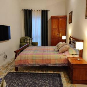 a bedroom with a bed and a chair and a television at Rons Town House in Tarxien