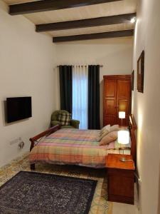 um quarto com uma cama, uma cadeira e uma televisão em Rons Town House em Tarxien