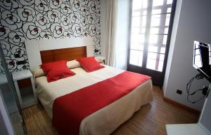 a bedroom with a bed with two red pillows at Hostal Centro in Soria