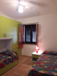 1 dormitorio con 2 camas y ventana con lámpara en Casa Deledda, en La Caletta
