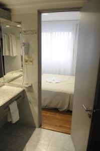 uma casa de banho com uma cama e um chuveiro com um espelho. em Hotel California em Montevidéu