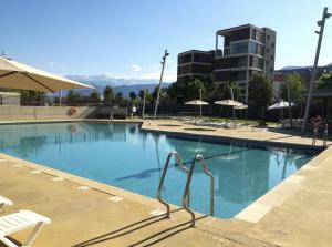 una gran piscina con sillas y sombrillas en Destino Deluxe Pirineos, en Sabiñánigo