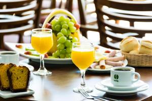a table with two glasses of orange juice and a plate of fruit at Hotel Golden Park Sorocaba & Convenções - by Nacional Inn in Sorocaba