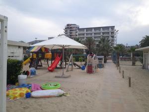 a beach with a playground with an umbrella and a slide at FRONTE MARE-CENTRALE-Riviera Palace-Giulianova-Apartment-nei mesi di Luglio e Agosto Prenotazioni solo da Sabato a Sabato in Giulianova