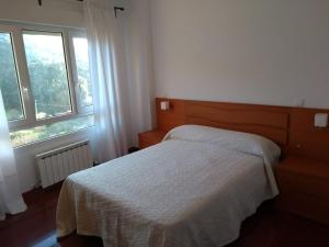 um quarto com uma cama e duas janelas em Apartamento Fuerte El Mazo em Santoña
