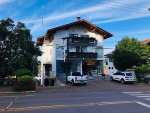 a white building with two cars parked in front of it at Alpen Hospedagem in Treze Tílias