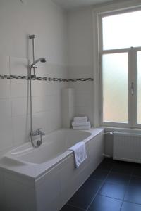 a white bathroom with a tub and a window at De Doelen in Leiden +56 photos
