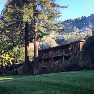 a house with trees in front of a green lawn at Big Sur River Inn in Big Sur