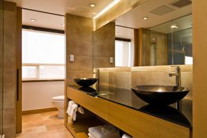 Baño con 2 lavabos y espejo en Ramada Plaza by Wyndham Prince George en Prince George