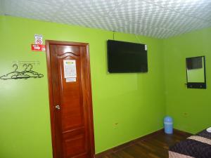 Habitación con paredes verdes y TV de pantalla plana. en Hostal Bolívar Inn, en Quito