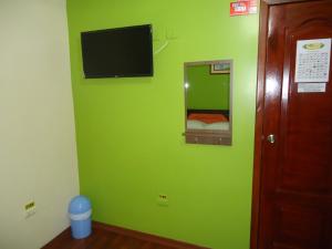 a green wall with a mirror and a television at Hostal Bolívar Inn in Quito