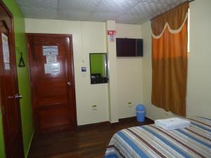 a room with a bed and a door with a television at Hostal Bolívar Inn in Quito