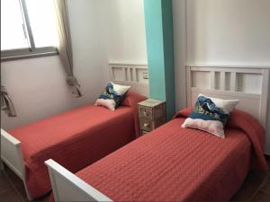 エル・メダノにあるSailor Home El Medanoの赤いシーツが備わる小さな部屋のベッド2台