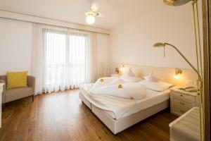 a bedroom with a large white bed and a mirror at Pension An Der Linde in Lagundo