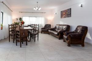 a living room with leather furniture and a table and chairs at ENIGMA BUCOVINEI in Vicovu de Jos