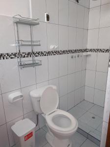 y baño blanco con aseo y ducha. en Hospedaje Inti en Pisac