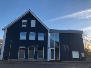 een groot blauw gebouw met een groot raam bij Den Skaldede Kok Guesthouse in Bindslev