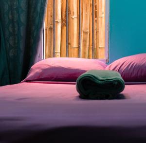 a green towel laying on a bed with two pillows at Cliff's Hostel in La Gruta