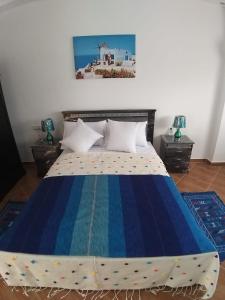 a bedroom with a bed with a blue and white comforter at TANJITAN HOSPITALITE in Tangier