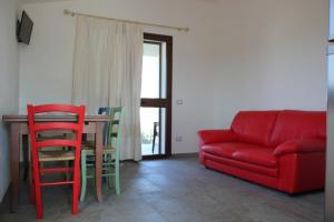 a living room with a red couch and a table at Oleandro in Lotzorai