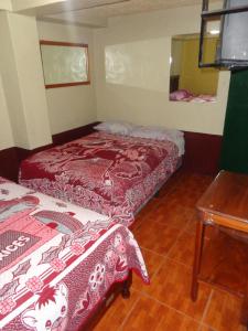 a small room with two beds and a table at Hotel Landivar Zona 7 in Guatemala
