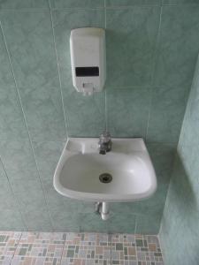 La salle de bains est pourvue d'un lavabo blanc et d'un distributeur de savon. dans l'établissement Hotel Landivar Zona 7, à Guatemala