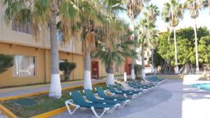 a row of lounge chairs next to a building with palm trees at Condo de Cortez in Puerto Peñasco
