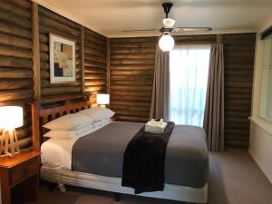 a bedroom with a bed with wooden walls and a window at Ti-Tree Village in Ocean Grove