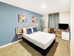 a hotel room with a bed, desk and a television at 28 Hotel in Sydney