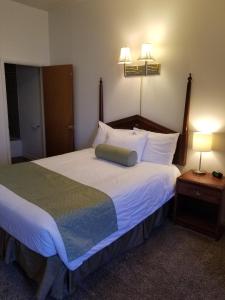 una habitación de hotel con una cama grande con sábanas blancas en Cattlemen Motel en Lovell