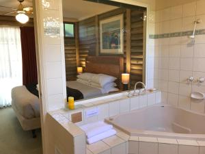 ein Badezimmer mit einer Badewanne und ein Schlafzimmer mit einem Bett in der Unterkunft Ti-Tree Village in Ocean Grove