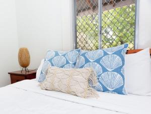 a bed with blue and white pillows and a window at Best Central House - SLEEPS 12 !! in Wagga Wagga