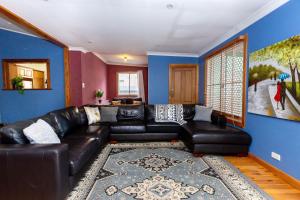 a living room with a black leather couch and blue walls at Best Central House - SLEEPS 12 !! in Wagga Wagga