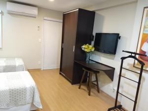 a bedroom with a bed and a tv on a wall at Apt 109 Mont Blanc Apart Hotel in Duque de Caxias