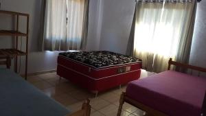 una habitación con 2 camas y una maleta roja en Pousada vila oeste en Itapoa