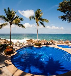 uma piscina com palmeiras e o oceano em Ocean Front, 3 bedroom, 3 bathroom, Casa Natalia, Playa Esmeralda em Puerto Vallarta