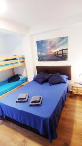 - une chambre avec un lit bleu et des serviettes dans l'établissement PRIMERA LÍNEA, PISCINA, WiFi, PÁDEL y más! #1, à El Campello