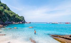 un hombre parado en el agua en una playa en Phuket Best Travel en Nai Yang Beach