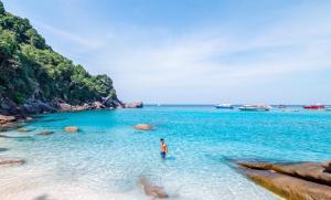 a man standing in the water on a beach at Phuket Best Travel in Nai Yang Beach