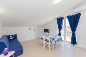 a living room with a blue couch and a desk at Apartments Snjezana in Pirovac