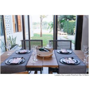 ein Holztisch mit Tellern und Gläsern darauf in der Unterkunft White Wall Riverfront Hotel in Kamphaeng Phet