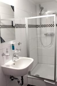 La salle de bains blanche est pourvue d'un lavabo et d'une douche. dans l'établissement Hotel Viktoria, à Meersburg