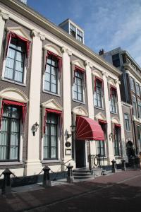 a large white building with a red awning on a street at De Doelen in Leiden