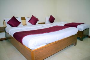 two beds in a room with purple and white pillows at Manas Homestay by Sky Stays in Saputara